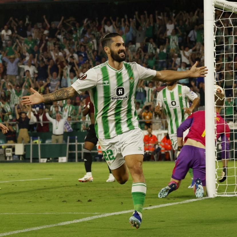 Isco celebrates during a Real Betis match in the club's green-and-white striped shirt.