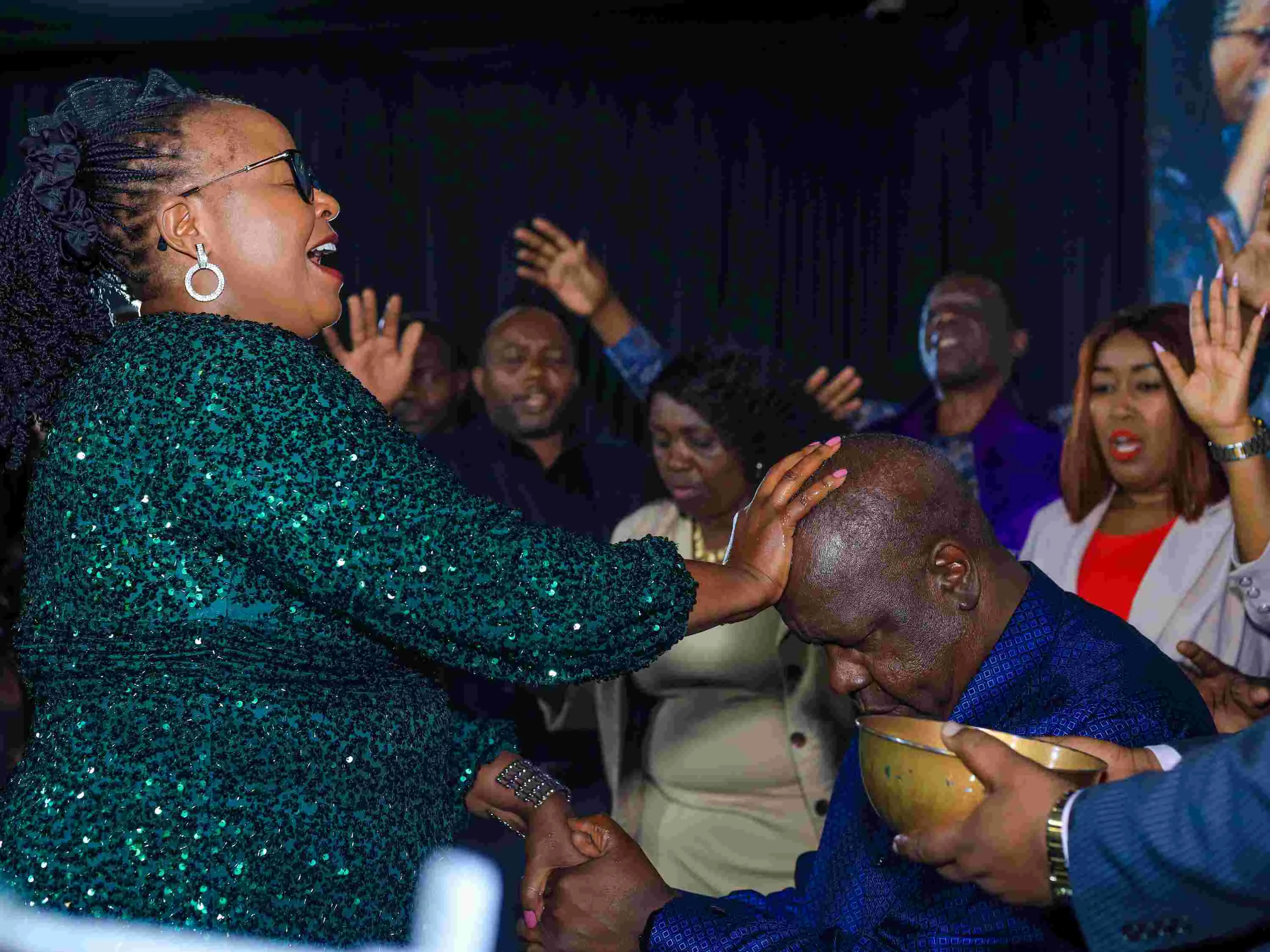 Bishop Margaret Wanjiru places her hand on Fred Matiang’i’s head during a church prayer service.