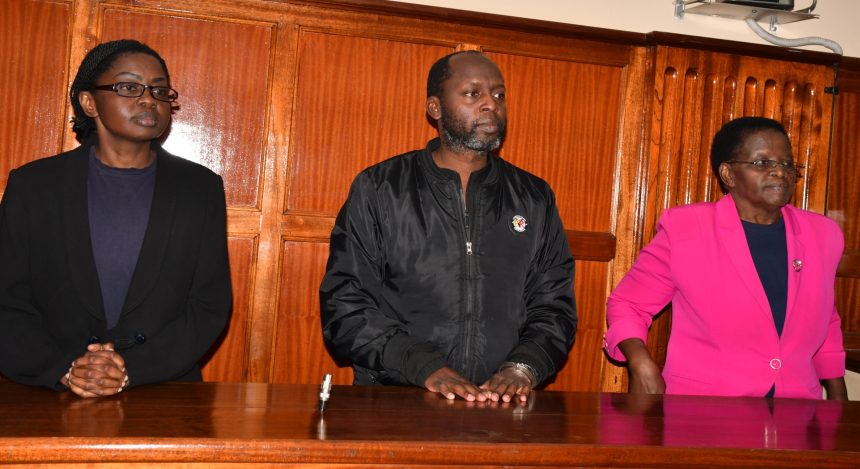 Individuals stand before the courtroom bench during proceedings related to the murder case of Dr Victoria Mutiso.